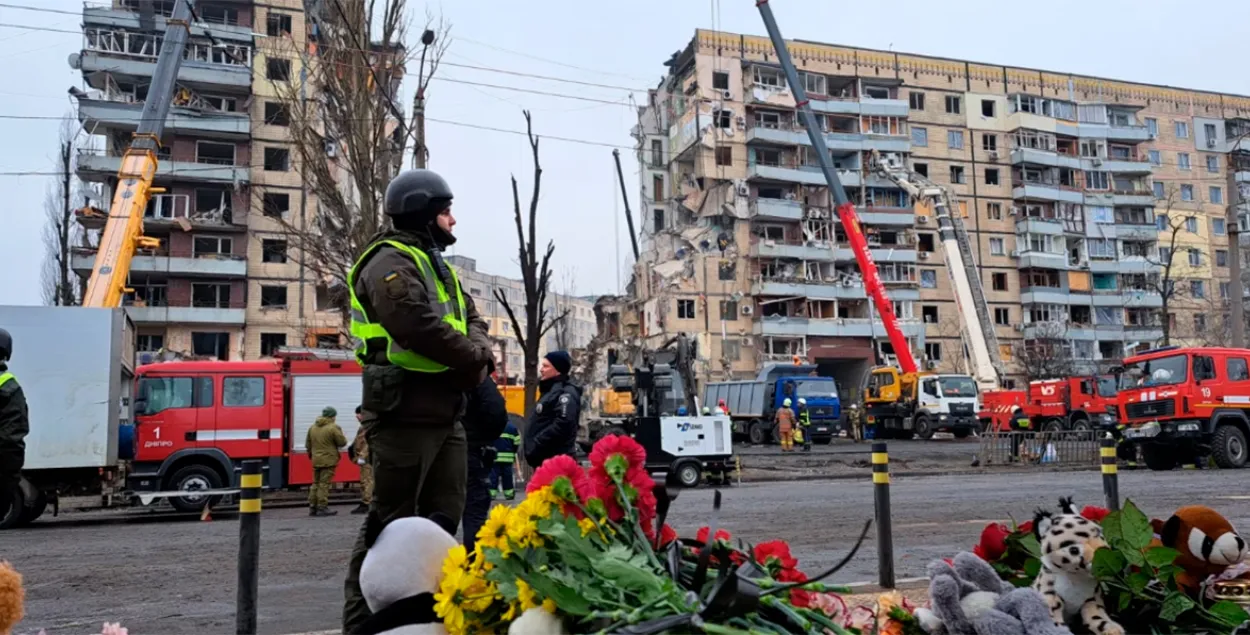 Люди несут цветы, свечи и игрушки к разрушенному зданию в Днепре / RFE/RL
