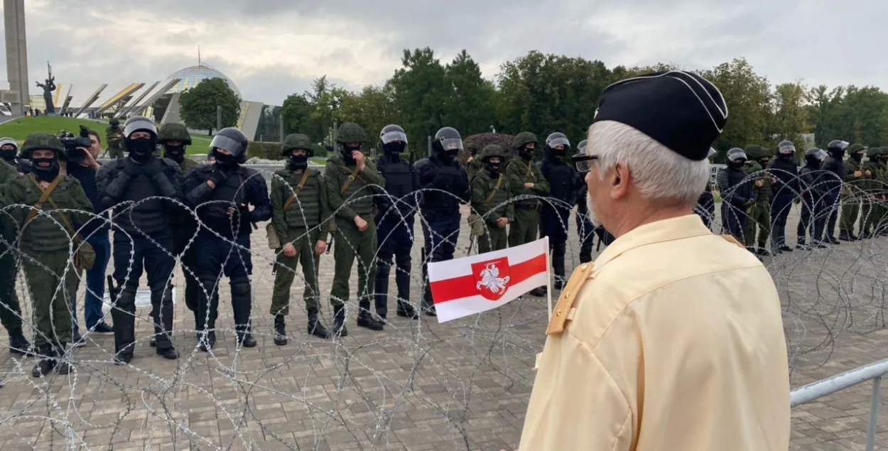 Пратэстовец стаіць насупраць ланцугу вайскоўцаў, трымаючы ў руках бел-чырвона-белы сцяжок 23 жніўня 2020 года / Еўрарадыё