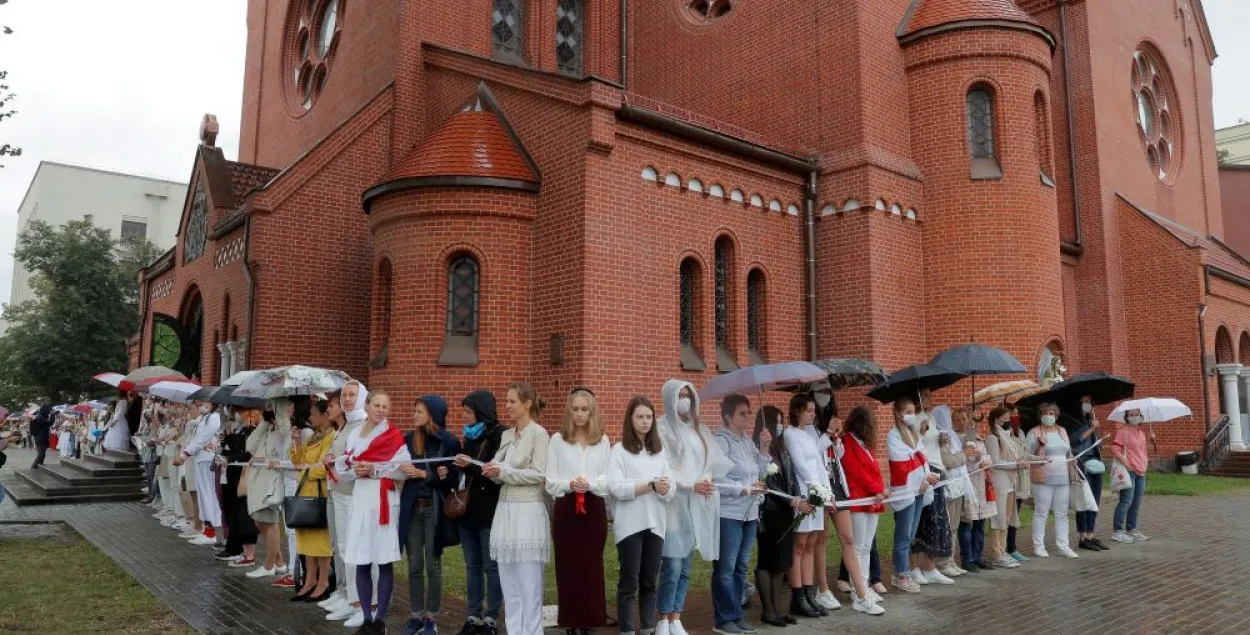 Женщины стоят в живой цепи перед костёлом святых Симеона и Елены в Минске, 27 августа 2020 года
