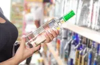 Жанчына трымае ў руках бутэльку алкаголю
