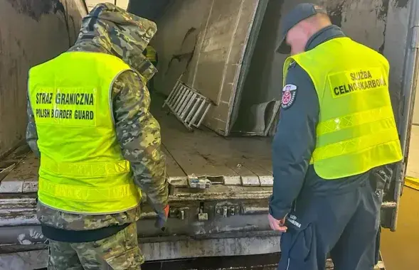 Памежнік і мытнік аглядаюць схованку ў падлозе фуры
